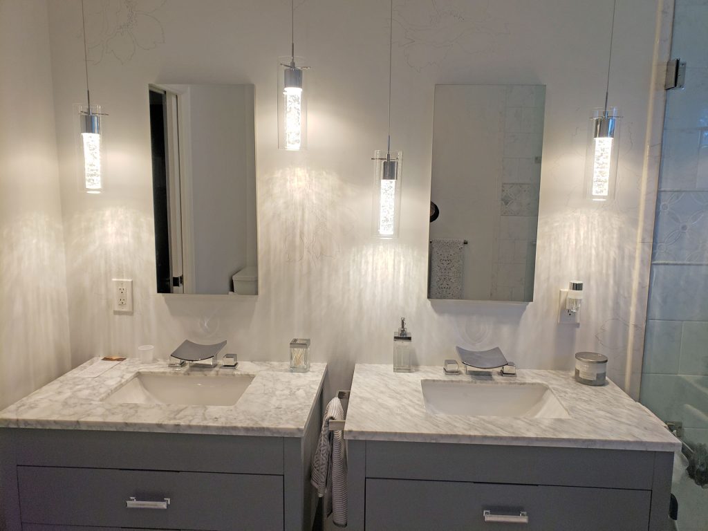 bathroom with two sinks, two mirrors, both have marble countertops, gray cabinets